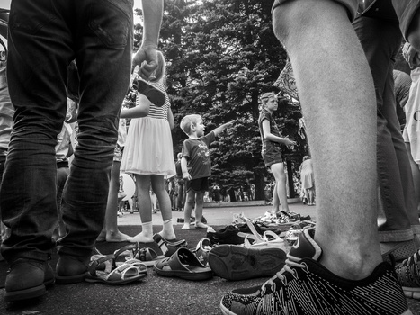 Children's shoes and legs circled around scattered roller skates on pavement.