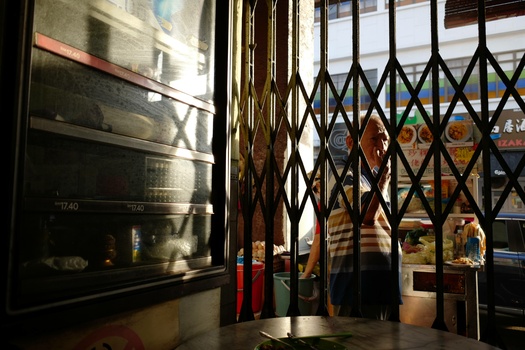 Interior storefront with accordion security gate partially closed in front of window display.