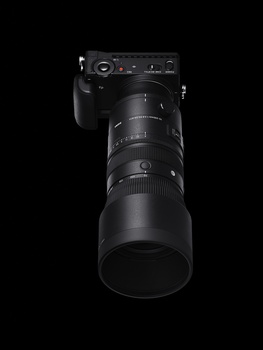 Telephoto lens mounted on a camera body, shown against a black background.