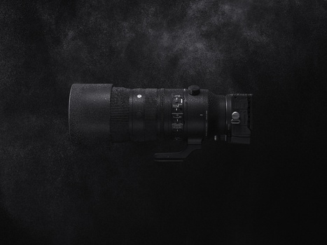Black telephoto lens with focus ring and adjustment controls mounted on dark textured background.