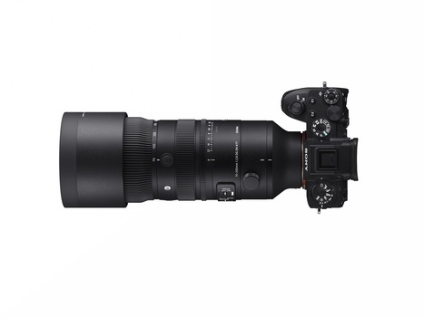 Mirrorless camera with telephoto lens mounted, shown in top-down view against white background.