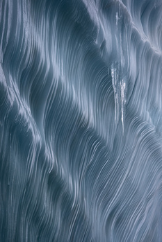 Abstract flowing streams of light and shadow creating diagonal wave patterns in cool blue and gray tones.