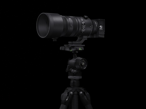 Telephoto lens mounted on a tripod with ball head against a black background.