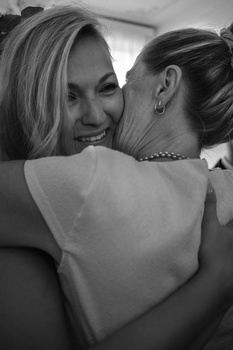 Two women embracing in close-up, black and white portrait photography.