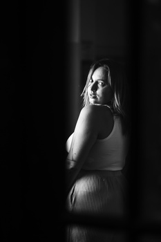 Woman in sleeveless top looking over shoulder in dramatic black and white lighting.