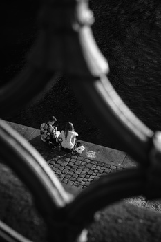 Bride's hands holding bouquet while sitting, photographed in high-contrast black and white.