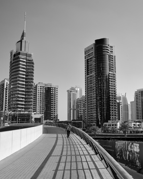 Black and white urban cityscape featuring residential towers along a waterfront pedestrian walkway.
