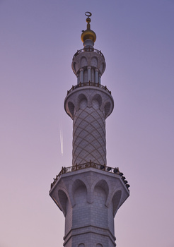 Ornate minaret tower photographed against a purple twilight sky at dusk.