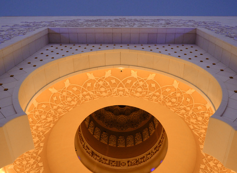Concentric circular architectural dome with ornate Islamic geometric patterns and warm golden lighting.