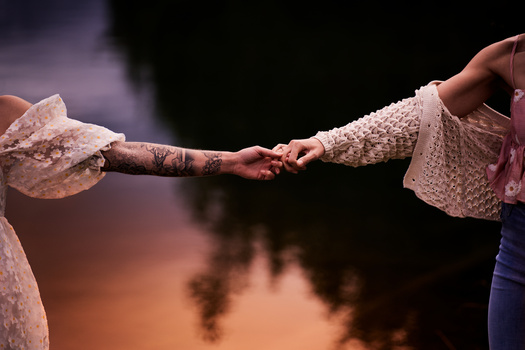 Two hands joining together against a blurred warm-toned background.