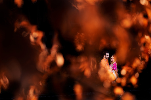 Two people framed by warm, blurred orange foliage in sharp focus.