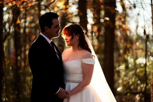 Bride and groom posing together in a sunlit forest during golden hour.