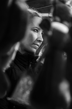 Black and white portrait of a man surrounded by blurred figures in close proximity.