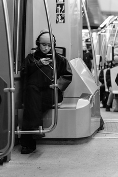 Black and white portrait of a person on public transit, looking directly at the camera with a contemplative expression.