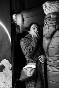 Woman in textured cardigan looking upward in dramatic low-key lighting setup.