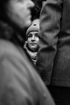 Young child's face framed between two adults in a close, intimate black and white portrait.