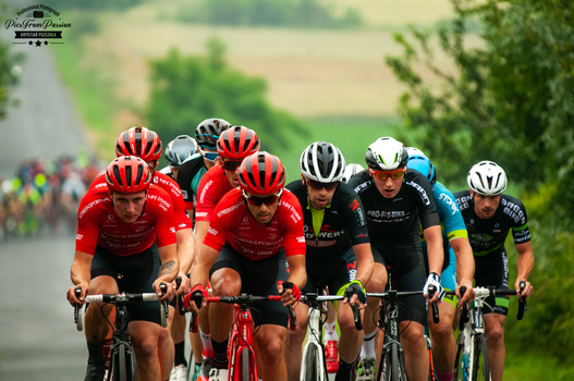Professional cyclists riding in formation during a competitive cycling event on a rural road.