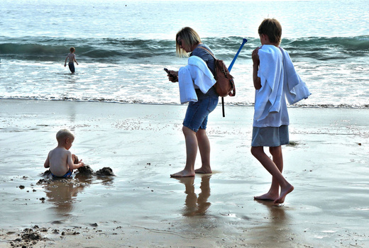 Children playing in shallow ocean water with snorkeling gear on a sunny beach day.
