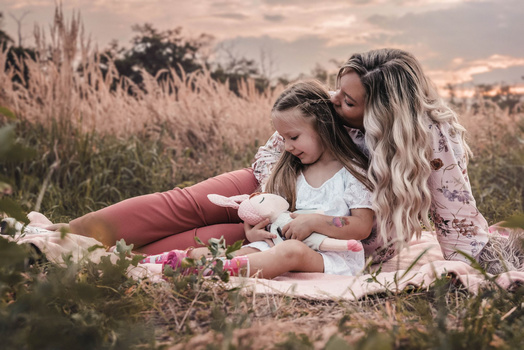 Woman and child sitting together in a field of wildflowers during golden hour.