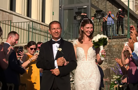 Bride and groom walking through cheering wedding guests in outdoor ceremony recessional.