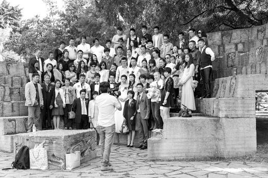 Large group of people gathered on stone steps and plaza, formally dressed in vintage clothing.