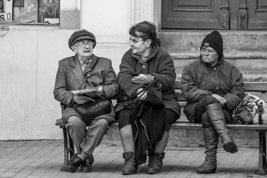 Three people sitting on steps in black and white street photography.