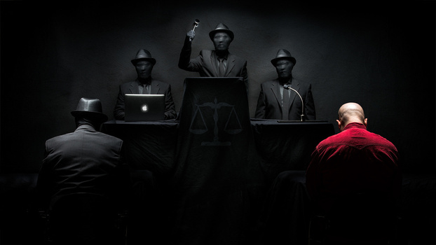 Two figures in suits face three seated judges in fedoras at an elevated bench during a formal proceeding.