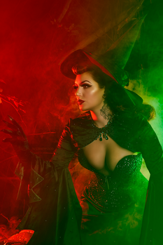 Woman in green sequined dress against red and green atmospheric lighting.