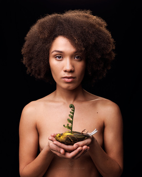 Woman with voluminous curly hair holding a bowl with a caterpillar perched on her hands.
