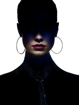 High-contrast portrait with subject's face obscured in shadow, glowing eyes, bold magenta lips, and large hoop earrings.