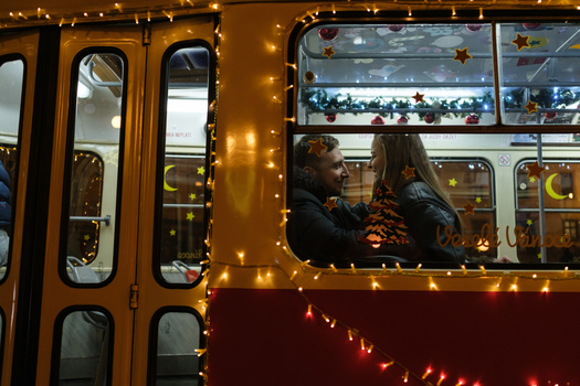 Couple sitting inside a vintage tram decorated with warm string lights during evening hours.