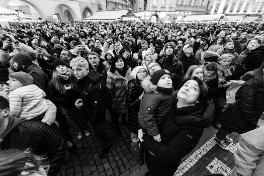 Large crowd of people gathered in an urban plaza, photographed in black and white.