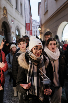 Group of young people smiling at camera on crowded European street with classical architecture.