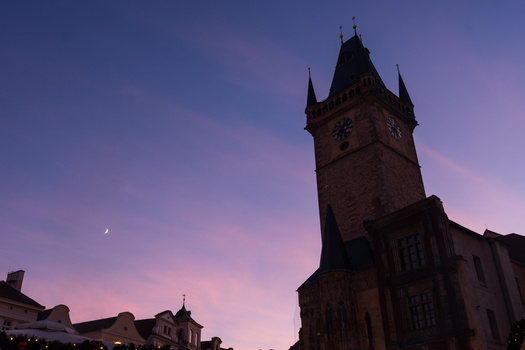 Gothic clock tower silhouetted against a twilight sky with purple and pink hues.