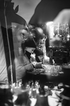 Black and white portrait of a person at a vanity mirror with theatrical lighting and reflections.