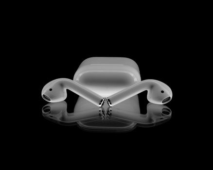 Wireless earbuds with charging case displayed symmetrically against a black reflective surface.