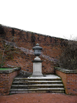 Stone pedestal and lantern centered within brick alcove framed by stepped walls.