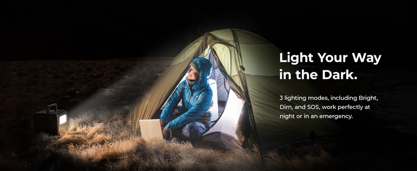 Camper inside illuminated tent at night, sitting cross-legged while reading by bright internal light source.