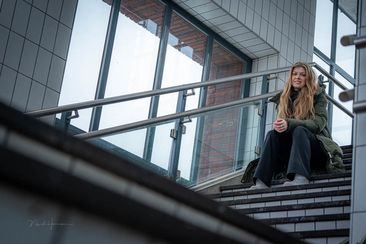Woman sitting on brick stairs against modern glass and metal building facade.