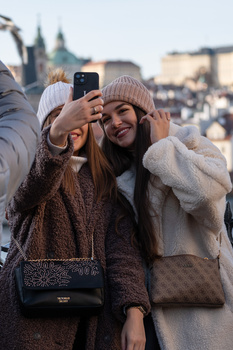 Two women taking a selfie together outdoors in winter clothing and beanies.