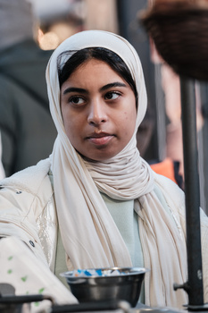 Young woman wearing a white headscarf and light-colored clothing, looking directly at camera with neutral expression.