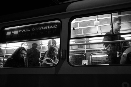 Black and white photograph of passengers visible through bus windows at night.