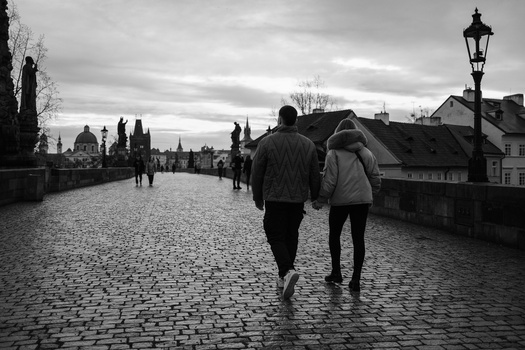 Two people jogging on a wet cobblestone bridge with historic architecture visible in the misty background.
