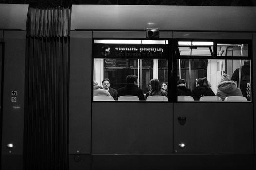 Black and white photograph of passengers visible through bus windows at night.