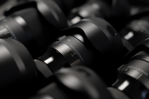 Collection of camera lenses arranged closely together in black and white.