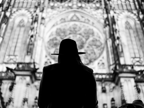 Silhouetted figure in hat facing ornate Gothic cathedral architecture in black and white.