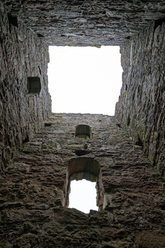 View through two stone archways looking upward toward bright sky, creating a centered rectangular frame within frame composition.