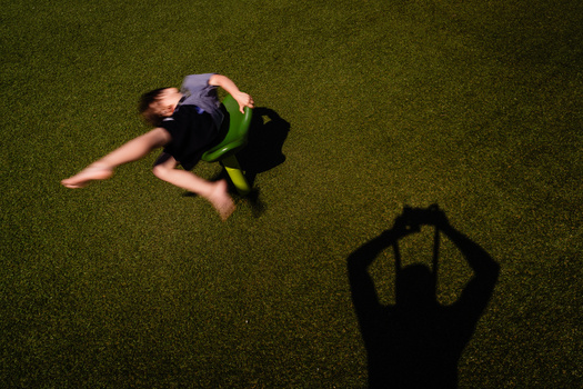 Overhead shot of a person lying on grass with one arm extended, their shadow visible beside them.