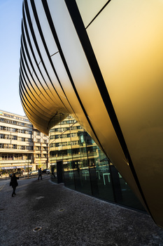 Modern curved black metal structure framing a residential building during golden hour sunset.