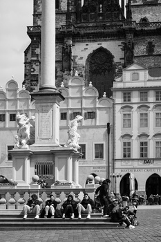 Black and white photograph of a public square with a monument and classical buildings in the background.